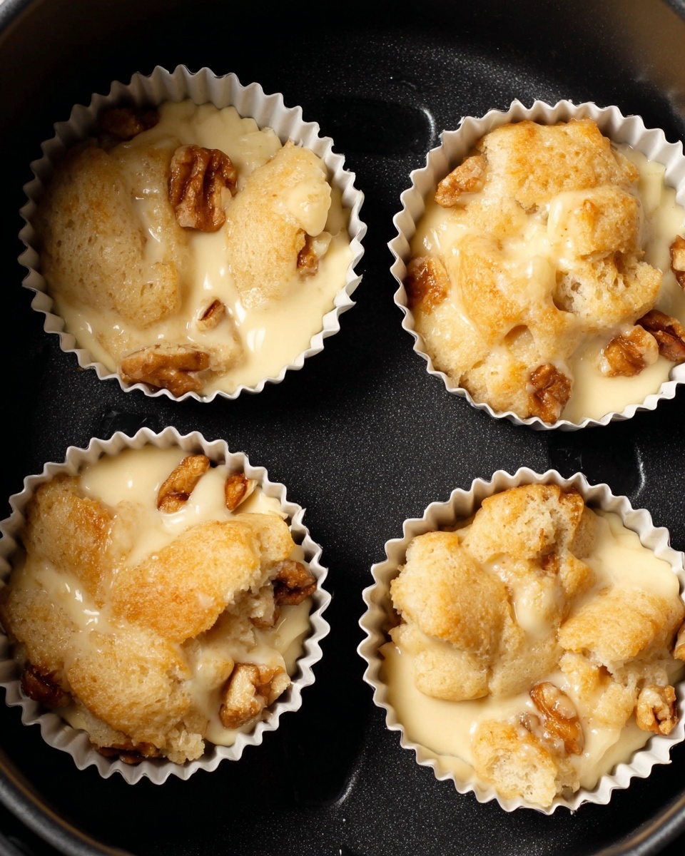 A close-up of a muffin with a golden brown, slightly rough top layer dusted with powdered sugar, sitting on a smooth white plate. Thick amber syrup is being poured over the muffin, flowing down its textured sides and pooling on the plate. In the blurred background, two more muffins rest on a wire rack on a white marbled surface. photo taken with an iphone --ar 4:5 --v 7
