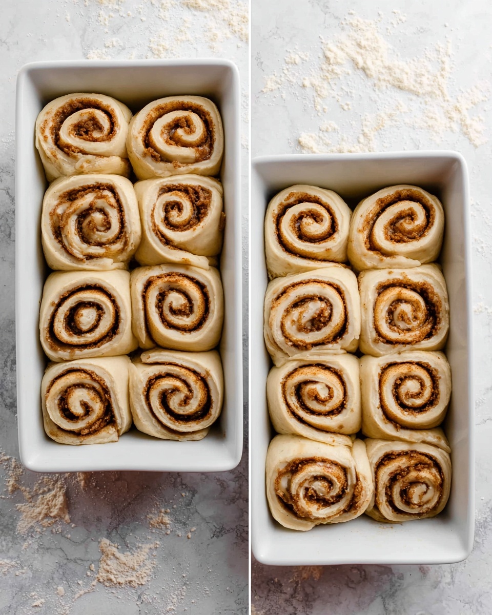 The image shows two white rectangular baking dishes filled with unbaked cinnamon rolls arranged in three rows and five columns. Each roll has a spiral shape with a light dough color on the outside and a darker cinnamon brown swirl in the center. The dough looks soft and slightly shiny, and the rolls are closely packed in the dishes, touching each other. The background is a white marbled texture with some small crumbs and flour scattered around. photo taken with an iphone --ar 4:5 --v 7
