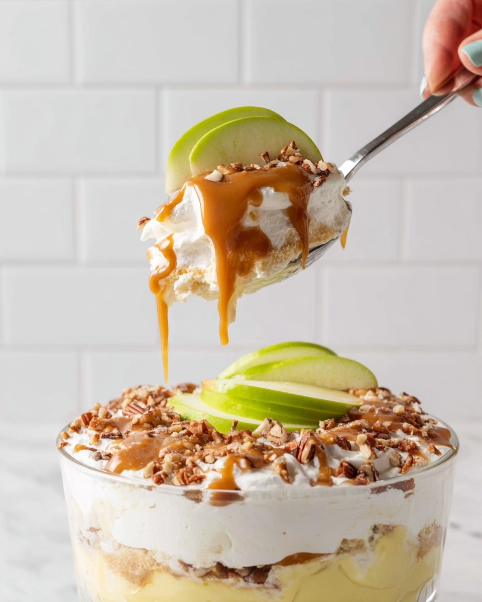 The image shows four glass cups filled with a layered dessert on a white marbled surface. Each cup has three main layers: a bottom layer of white creamy yogurt with small black specks, a middle layer of granola mixed with caramel-colored sauce and diced cinnamon-spiced apples, and a top layer of more diced apples coated in a shiny caramel sauce that drips down the sides of the cups. In the foreground, a woman's hand holds a spoon with a scoop of the dessert, showing the creamy white yogurt beneath the apple topping. Green apple slices and a whole green apple are placed on the surface around the cups, adding fresh color. The background is softly blurred with dark tones, highlighting the dessert cups and the white marbled surface photo taken with an iphone --ar 4:5 --v 7