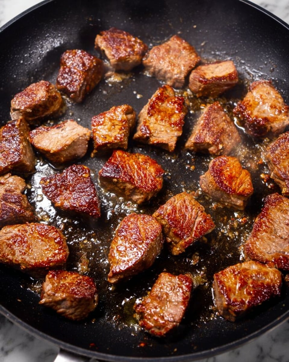 The image shows a black pan filled with a thick, brown sauce that has a glossy texture. Inside the sauce, there are many slices of light brown mushrooms and thin slices of translucent white onion, evenly spread throughout the pan. The sauce looks rich and slightly speckled with herbs or seasoning. The background surface is a white marbled texture. Photo taken with an iphone --ar 4:5 --v 7