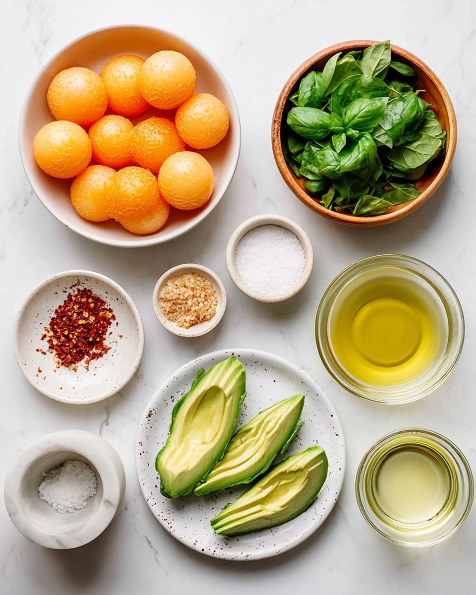 The image shows a white marbled surface with nine small white dishes and bowls arranged neatly. On the left, a large white bowl holds many round orange melon balls. Above it, a small white bowl contains coarse salt, and next to it, a wooden bowl is full of bright green fresh basil leaves. Below the basil is a small white dish with red chili flakes and another with a light brown crumbly ingredient. To the right, a small bowl contains a small amount of minced garlic. Two halves of avocado, sliced thinly and fanned out, sit on a white plate with a few black speckles. On the far right, there are two clear glass cups, one filled with olive oil and the other with a light beige liquid. A small white marble mortar with salt is positioned near the avocado. Photo taken with an iphone --ar 4:5 --v 7