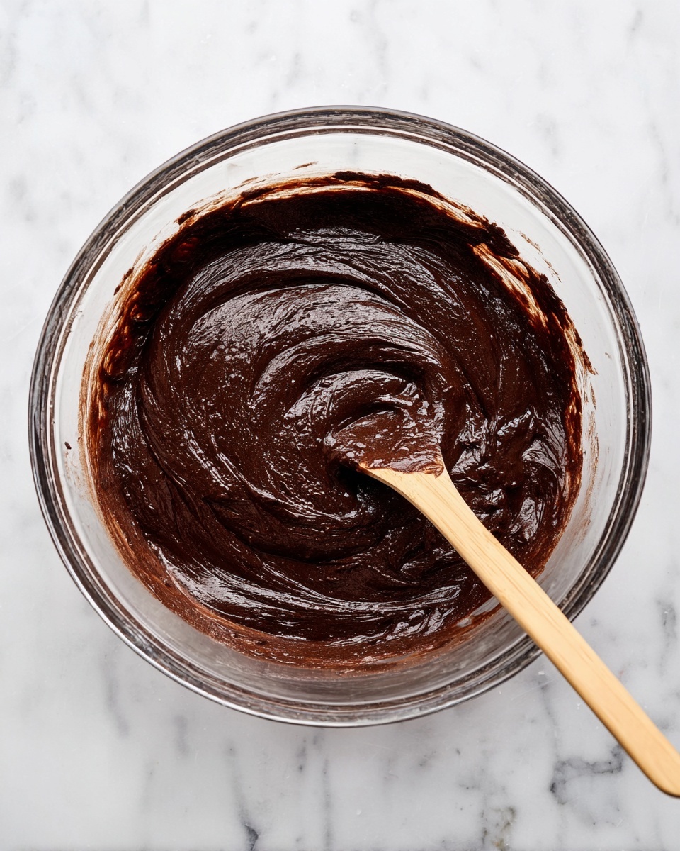 A single-layer square chocolate brownie baked in a foil-covered metal dish, with a textured dark brown surface dotted with small, scattered chocolate chips, resting on a white marbled surface photo taken with an iphone --ar 4:5 --v 7