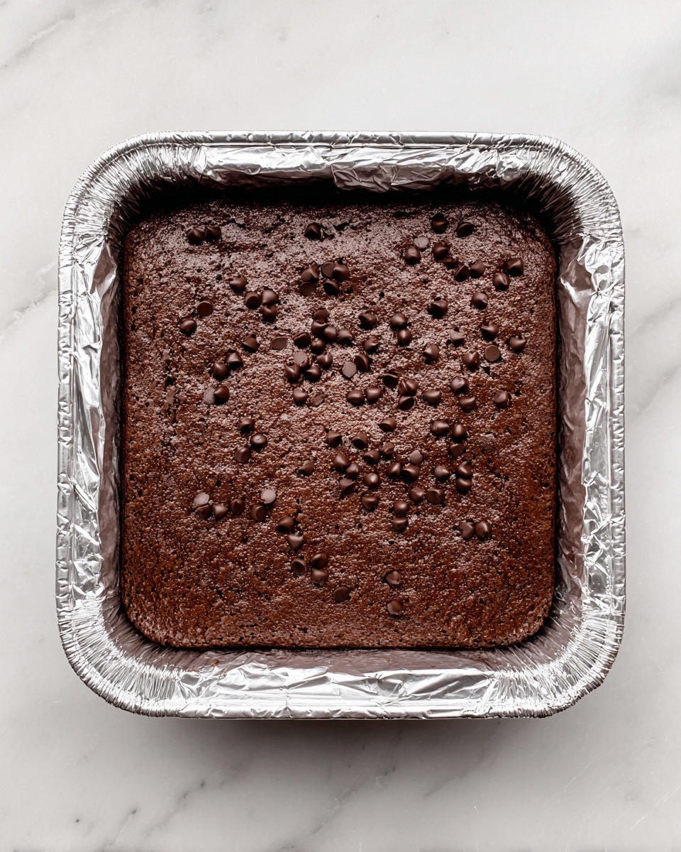 A close-up of a stack of four thick, dark brown brownies with a rich, moist texture filled with shiny melted chocolate swirls. Each brownie layer shows a slightly cracked, crisp top that contrasts with the dense, soft inside. The background is a dark blurred surface, and the brownies rest on a light brown parchment paper over a white marbled surface. Next to the stack, there is another pile of brownies slightly out of focus. photo taken with an iphone --ar 4:5 --v 7