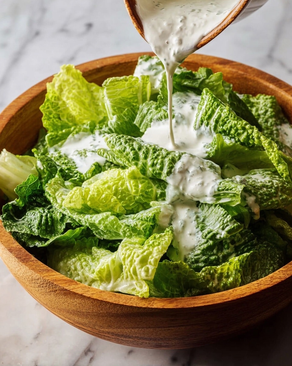 The image shows a wooden bowl filled with fresh green romaine lettuce leaves that have a crisp, slightly wrinkled texture and varying shades of green from dark to light. Thick white dressing is being poured over the lettuce from above, creating a creamy, smooth layer that contrasts with the leafy greens. The bowl sits on a white marbled surface, adding a clean background to the natural colors of the salad. photo taken with an iphone --ar 4:5 --v 7