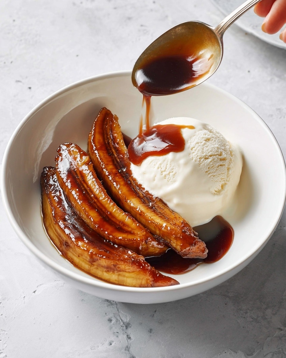 A white bowl contains three caramelized banana slices that are rich brown and shiny, placed on the left side of the bowl. On the right side, there is a scoop of smooth, creamy white ice cream. A spoon held by a woman's hand pours dark brown sauce over the ice cream and bananas, adding a glossy texture. The bowl is set on a white marbled surface. Photo taken with an iphone --ar 4:5 --v 7