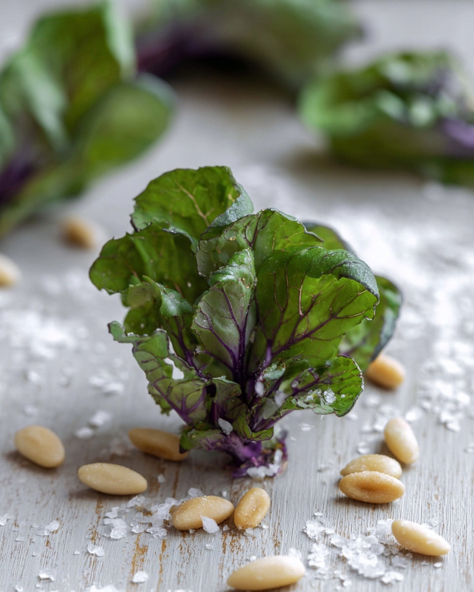 The image shows a close-up of a small leafy vegetable with ruffled green leaves edged with a hint of purple. The vegetable has about three to four main leafy layers expanding outward from a purple stem base. Around it on a wooden surface, several light tan pine nuts with a slightly toasted appearance are scattered along with coarse white salt crystals. The background shows blurred similar vegetables and more pine nuts, all set on a white marbled texture. Photo taken with an iphone --ar 4:5 --v 7