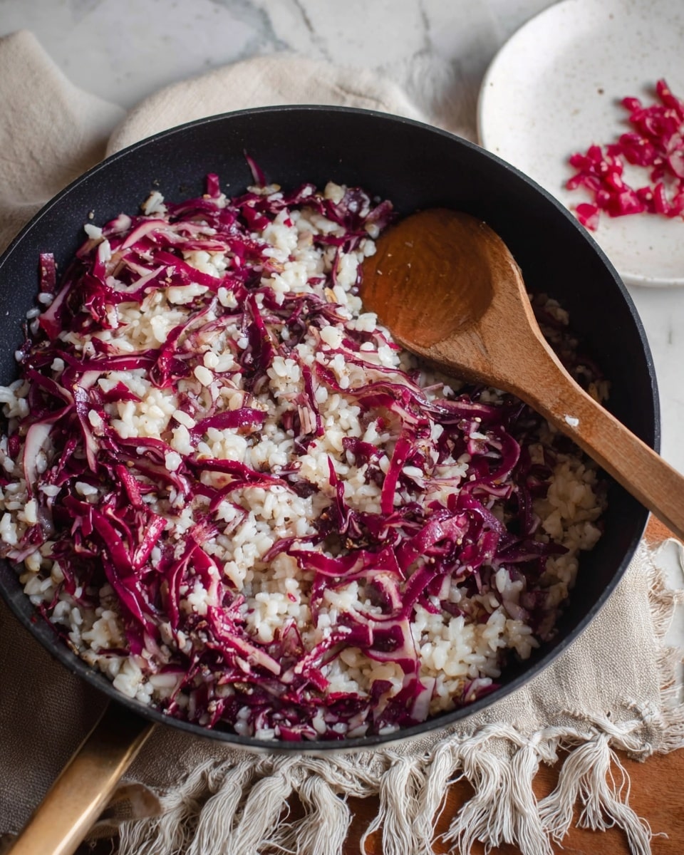 A bowl filled with creamy risotto mixed with browned sausage pieces and caramelized onion strips, topped with a sprinkle of grated white cheese and a small green rosemary sprig for garnish. The risotto shows a soft, slightly shiny texture with visible grains and bits of sausage and onion throughout. A silver spoon rests inside the bowl on the right side. The bowl is white with a deep round shape and sits on a light beige textured cloth, placed on a white marbled surface. In the background, a small white bowl of grated cheese and a glass of pale yellow wine are slightly out of focus. Photo taken with an iphone --ar 4:5 --v 7