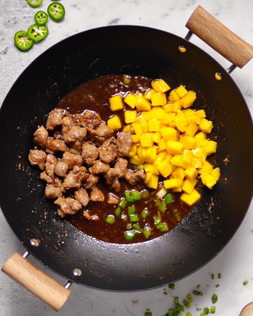 The image shows a white bowl filled with a layered dish made of small brown fried pieces covered in a rich, shiny sauce, mixed with bright orange mango cubes and small green onion slices scattered on top. The bowl rests on crumpled brown paper and a piece of rough jute fabric, all set on a dark surface with some green onion stalks and a wedge of mango in the background. The colors in the dish are vibrant with the bright orange mango standing out against the darker brown pieces and sauce. Photo taken with an iphone --ar 4:5 --v 7
