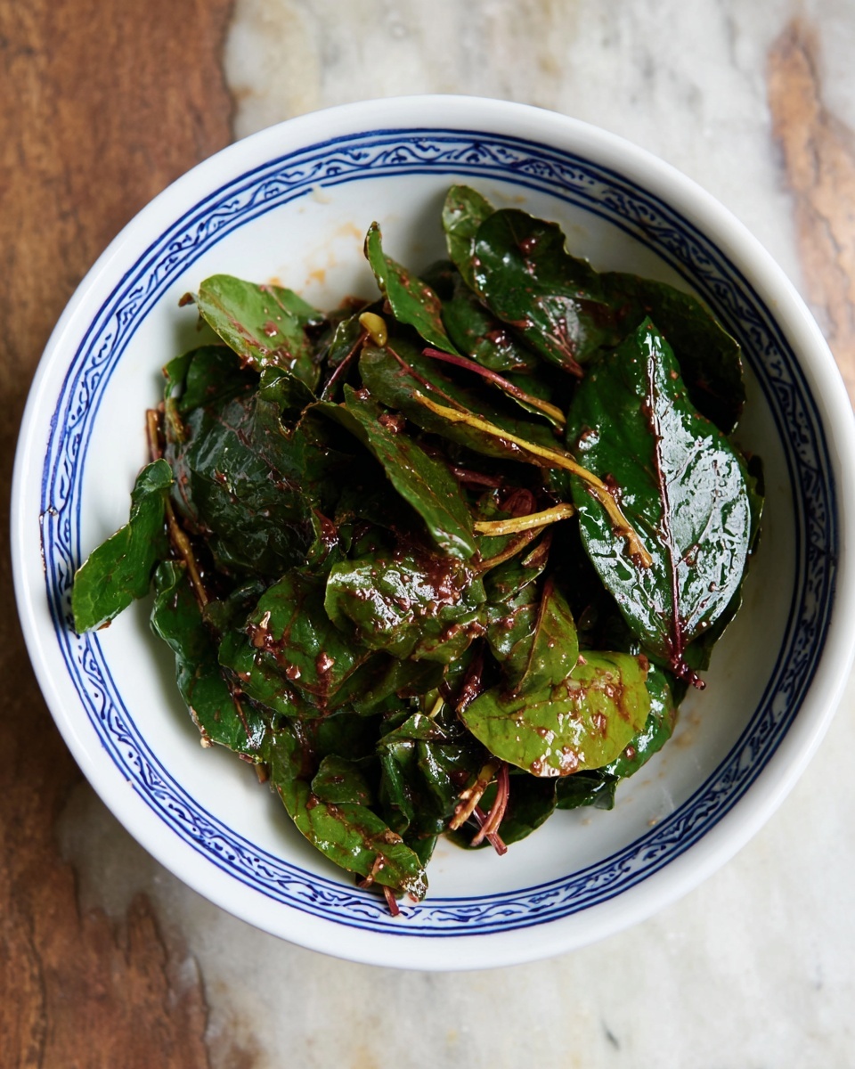 Apple Brie Salad with Raspberries and Pecans Recipe 5 A white bowl with blue edging holds a colorful salad. The bottom layer is green leafy spinach. On top of that are thin apple slices arranged in small fanned-out stacks, showing their light pinkish skin and creamy flesh. Bright red raspberries are scattered evenly over the salad. Small cubes of white cheese are placed throughout, along with whole and chopped dark brown pecans. The bowl sits on a crocheted beige cloth over a wooden table, with a glass jar of pecans and whole apples in the background. photo taken with an iphone --ar 4:5 --v 7
