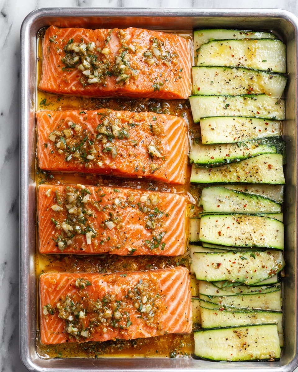 A metal baking pan holds four rectangular pieces of raw salmon on the left side. Each salmon piece is bright orange with visible white lines and is sprinkled with black pepper. On the right side of the pan, long, thin slices of pale green zucchini with dark green edges are laid out in a single layer, also sprinkled with black pepper. The background is a white marbled surface and a part of a blue and white striped cloth is visible at the upper left corner. photo taken with an iphone --ar 4:5 --v 7