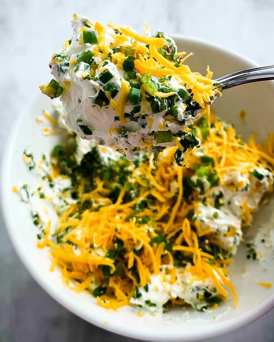 The image shows several small, golden brown crispy cups arranged on white parchment paper, placed on a round wooden board with dark bark edges. Each cup has a slightly folded shape with four pointed corners. Inside the cups, there is a creamy white filling with small green herbs mixed throughout, topped with melted yellow cheese. Thin green chives are scattered on and around the cups for garnish. In the background, there is a white scalloped bowl filled with dark brown sauce on a white marbled surface. photo taken with an iphone --ar 4:5 --v 7