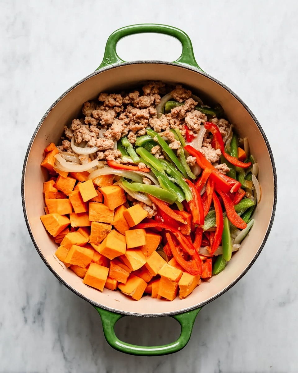 The image shows a green pot with two handles on a white marbled surface. Inside the pot, there are three main layers of ingredients: at the bottom, orange cubes of cooked sweet potatoes scattered evenly; mixed throughout are long strips of red and green bell peppers, and light yellow onion slices, creating a colorful bed. On top of the vegetables, there is a layer of cooked minced meat with a light brown color, placed mostly on one side of the pot. The pot's inner surface is cream-colored, adding contrast to the vibrant food colors. Photo taken with an iphone --ar 4:5 --v 7