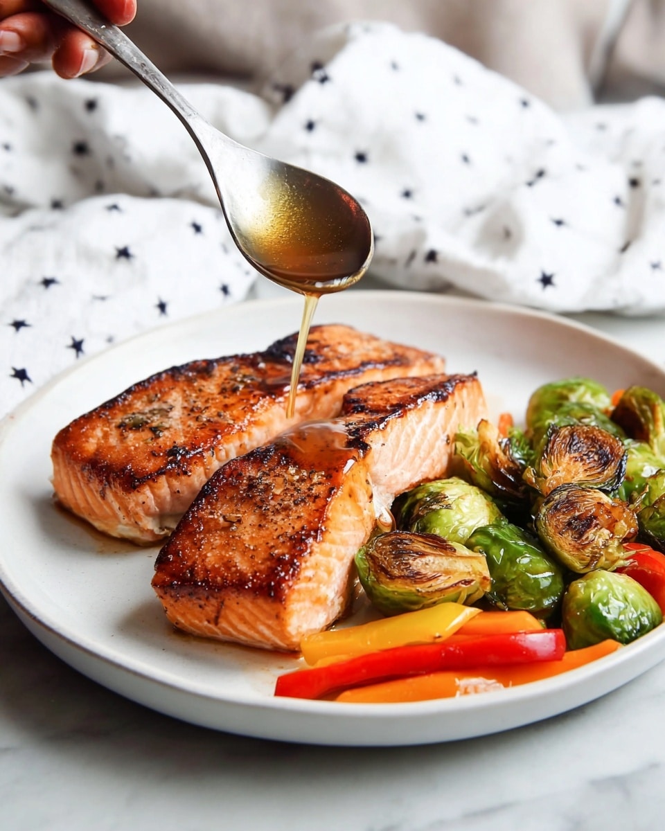 On a white plate with a white marbled surface underneath, there are two thick, golden-brown salmon steaks with a crispy, slightly charred skin edge and tender pink-orange flesh inside. Below the salmon, there are bright green roasted Brussels sprouts with some charred spots, and thin strips of roasted red and orange bell peppers placed next to them. Above the plate, a woman's hand holds a silver spoon, dripping a shiny amber sauce onto the front salmon steak. In the background, a white cloth with small black star designs is partially visible. Photo taken with an iphone --ar 4:5 --v 7