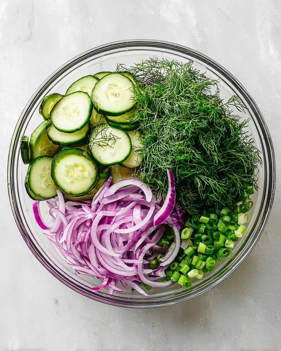 A clear glass bowl sits on a white marbled surface, filled with four distinct layers of fresh vegetables arranged separately. One layer shows thin, round green cucumber slices with dark green edges, stacked in a neat pile on one side. Next to it is a generous bunch of bright green dill with fine, feathery leaves. Below the dill, there are thin, curved slices of purple-red onion with a translucent texture. The last section contains a pile of chopped green onions in small round pieces. The colors contrast well, showing green and purple tones clearly, making the bowl look fresh and healthy. photo taken with an iphone --ar 4:5 --v 7