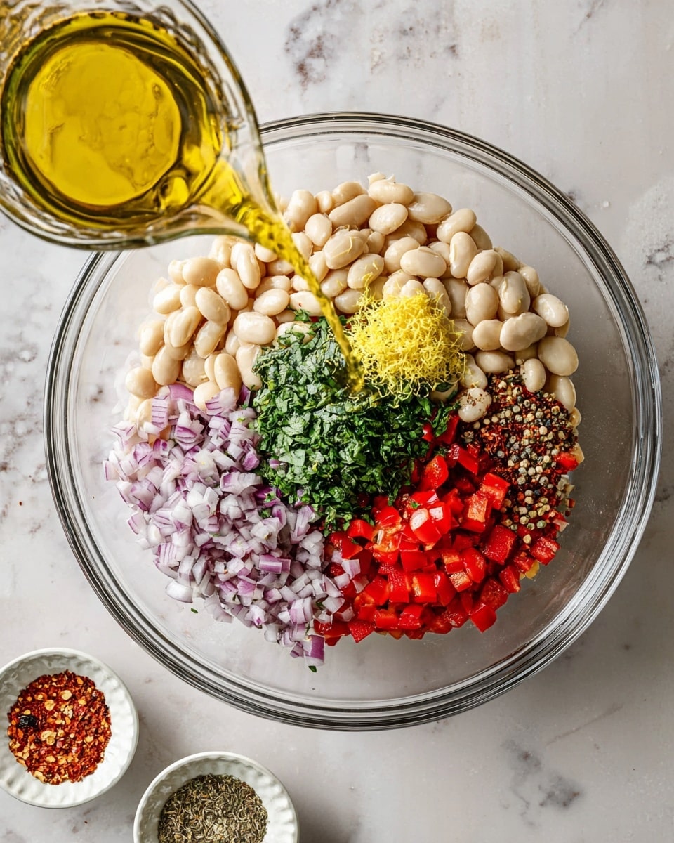 A white plate on a white marbled surface holds a fresh salad with two clear layers: the bottom layer is green arugula leaves, spread out with a light texture, and the top layer is a mix of pale white beans, finely chopped red bell peppers, small pieces of red onion, and green herbs, all mixed together with black pepper sprinkled lightly on top. A silver fork rests on the plate, partly covered by the salad. Around the plate are small white bowls with black pepper and red pepper flakes, some scattered green herbs, and a white cloth with thin black stripes. Photo taken with an iphone --ar 4:5 --v 7