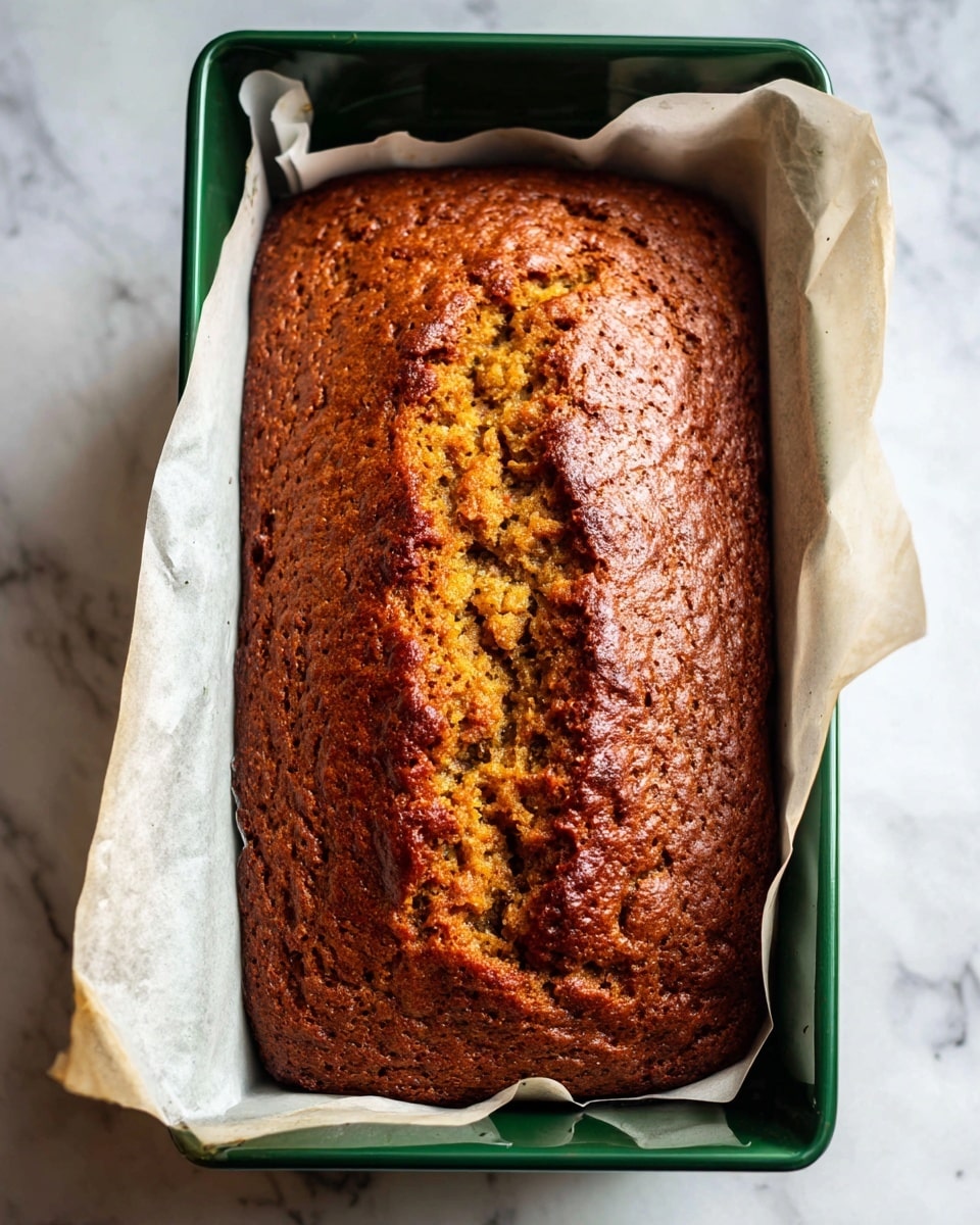A close-up view of a light yellow batter with a thick, slightly lumpy texture in a white speckled bowl. The batter fills most of the bowl, with a metal whisk partially submerged on the right side, showing the mix being stirred. The background is a white marbled texture. photo taken with an iphone --ar 4:5 --v 7