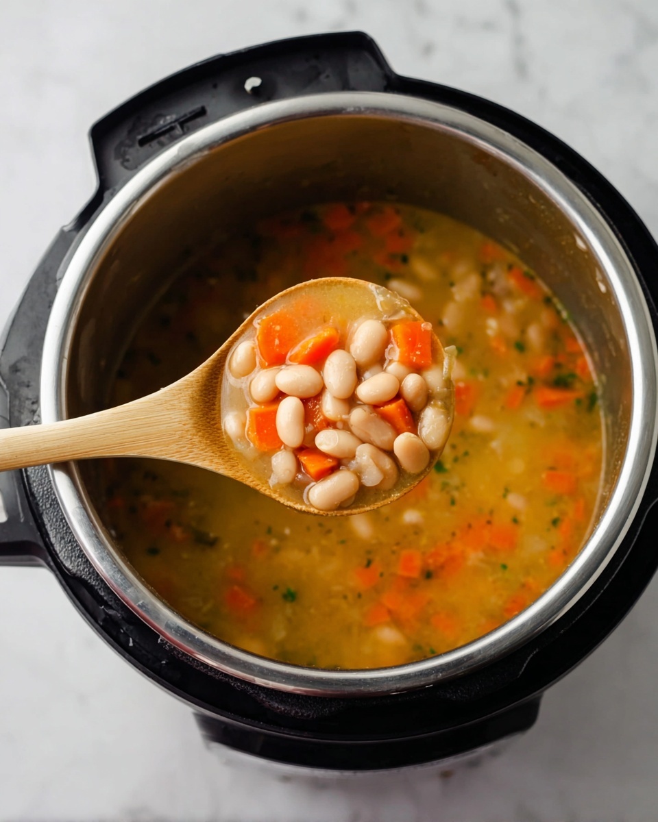 A close-up of a silver metal cooking pot inside a black Instant Pot, showing soup with white beans, orange carrot pieces, and small green bits in a light yellow broth; a wooden spoon with a light brown handle holds a scoop of the soup above the pot, displaying the beans and vegetables clearly. The pot is placed on a white marbled surface photo taken with an iphone --ar 4:5 --v 7