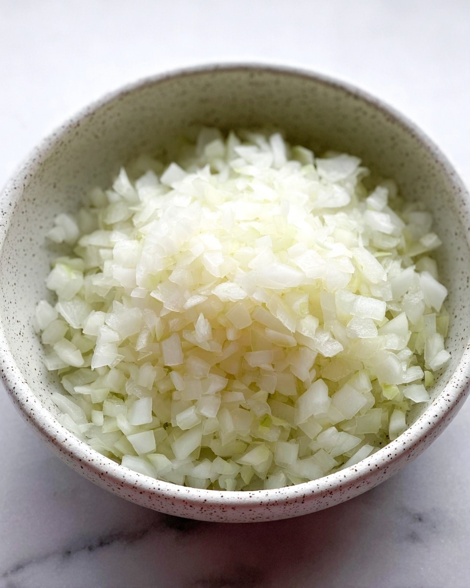 A close-up view of a grey bowl filled with many red cherry tomatoes, some whole and some cut in halves, showing the juicy inside with seeds and light reflections on the smooth skins. The bowl sits on a white marbled surface. photo taken with an iphone --ar 4:5 --v 7