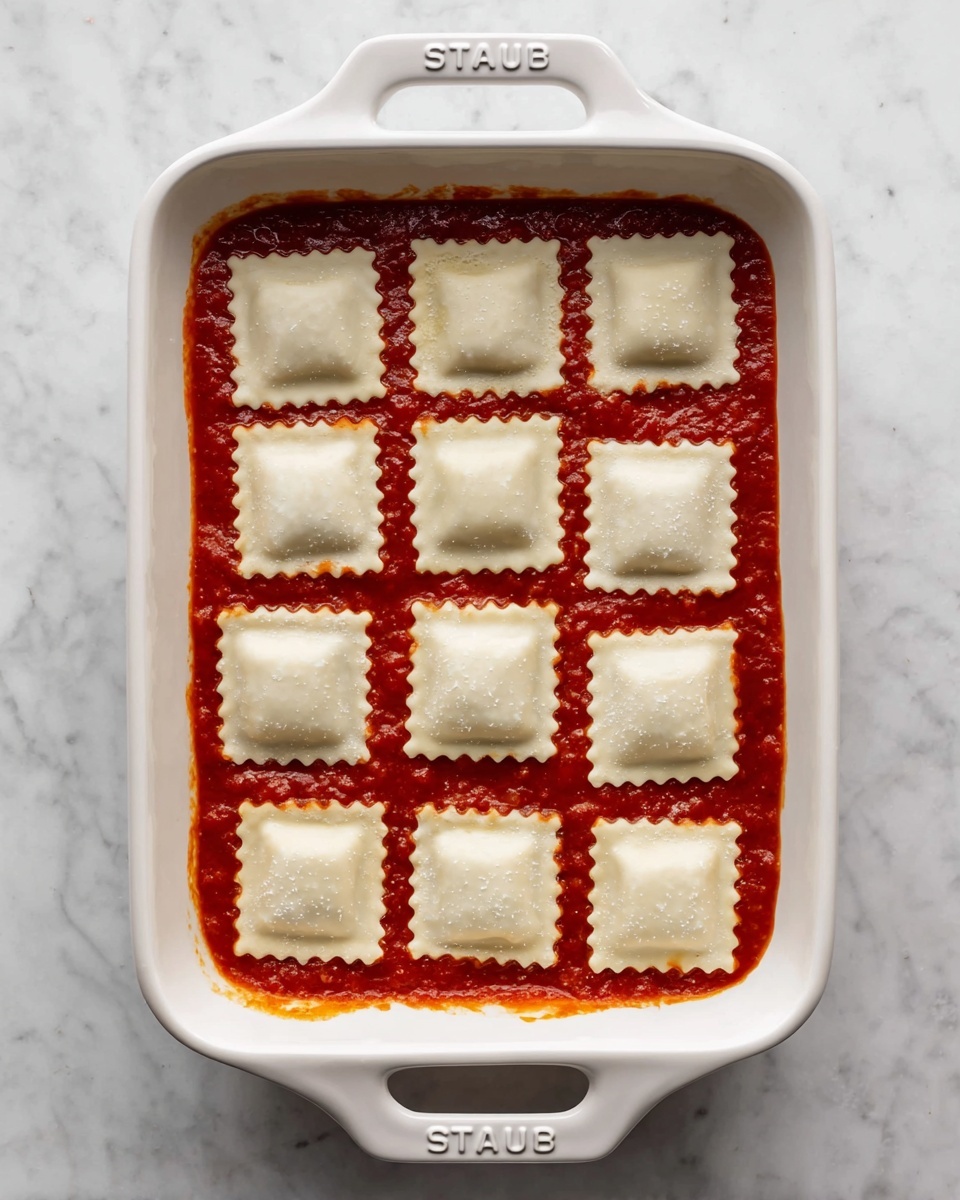 The image shows a white frying pan filled with a thick mixture of browned ground meat and wilted dark green spinach leaves, all coated in a rich red tomato sauce. The mixture has a slightly oily texture with small chunks of meat evenly distributed throughout the sauce, and spinach leaves scattered on top and underneath. The pan handle is silver and extends out of the frame, sitting on a white marbled surface. The photo taken with an iphone --ar 4:5 --v 7