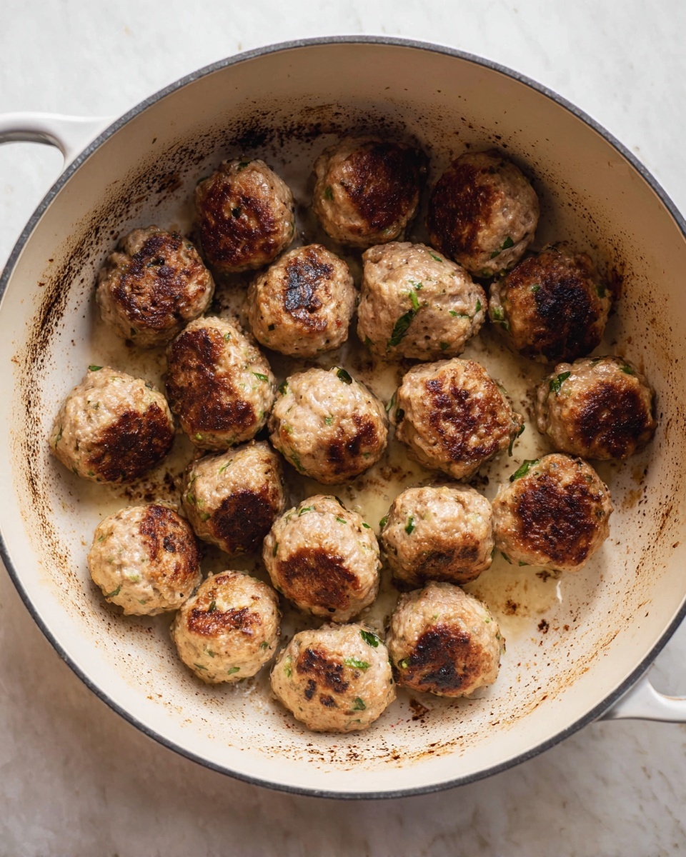 A round white pot with two handles holds a baked dish with one visible layer of rich red tomato sauce topped with melted white cheese that is creamy with browned spots, scattered with green basil leaves on top. The edges of the pot show a bit of sauce bubbling over. The pot sits on a white marbled surface with some grated cheese sprinkled around. A green basil leaf is also placed near the bottom right of the pot. Photo taken with an iphone --ar 4:5 --v 7