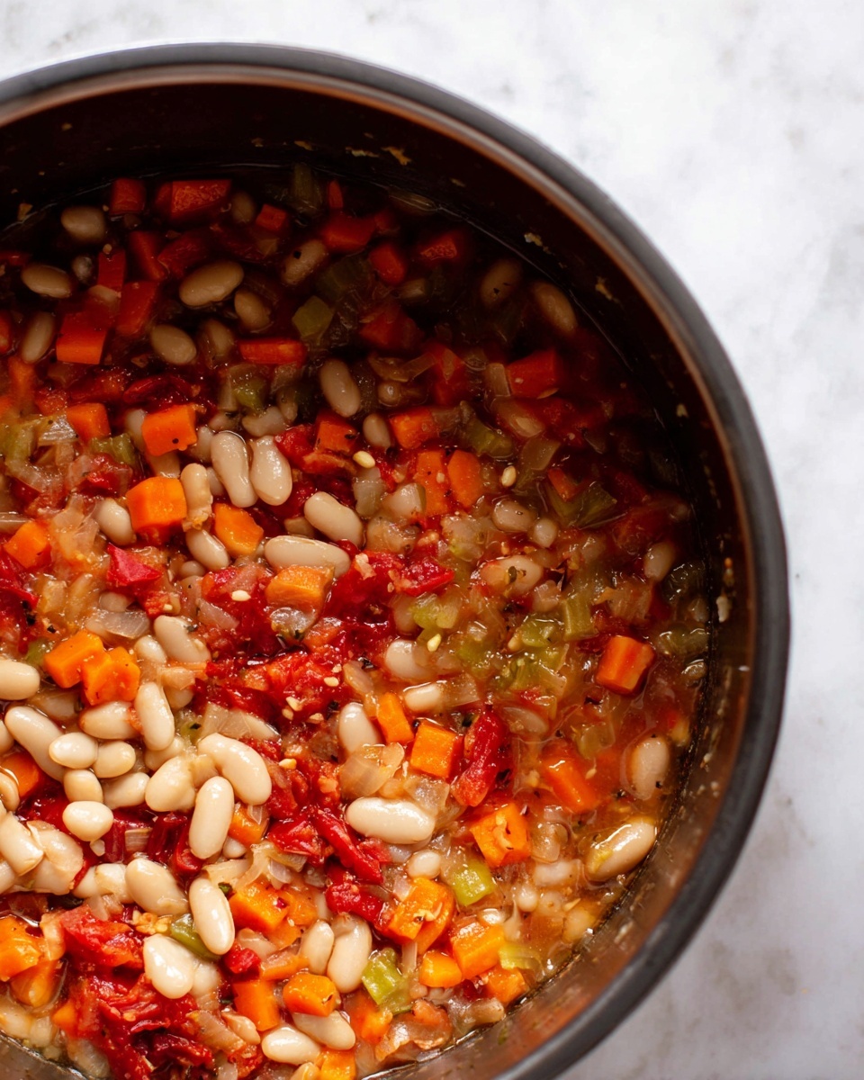 The image shows a white bowl filled with a thick soup that has visible layers of small white beans, orange carrot chunks, light green celery pieces, and small bits of tomato in a light brown broth. On top of the soup, there is a generous layer of crispy, toasted bread cubes with a golden brown color, sprinkled with grated white cheese and black pepper. A gold spoon is placed inside the bowl, resting on the soup near the edge. The bowl is set on a surface with a white marbled texture with some crumbs scattered around. Part of a second bowl with the same soup is visible at the lower right corner. Photo taken with an iphone --ar 4:5 --v 7