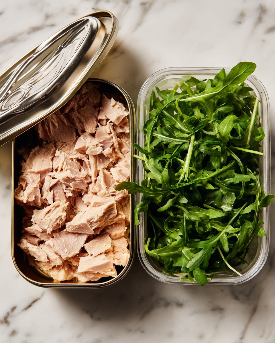 The image shows an open tin can on the left side filled with light pinkish-beige pieces of cooked tuna with a shiny silver lid partially lifted to reveal the tuna inside. On the right side, there is a clear plastic container filled with fresh, bright green arugula leaves showing their jagged and elongated shape. Both containers are placed on a white marbled surface. photo taken with an iphone --ar 4:5 --v 7
