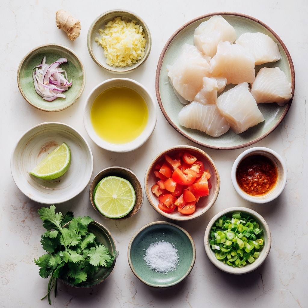 A white bowl filled with a creamy orange soup that has visible chunks of white fish, red tomato pieces, and small green herbs floating inside. On top, there are thin slices of red chili pepper with seeds showing, several wedges of bright green lime partially submerged, and a bunch of fresh green cilantro leaves resting on one side. A silver spoon is placed in the bowl near the lime wedges. The background is a white marbled texture with a partially visible second white bowl of soup and a halved lime nearby. Photo taken with an iphone --ar 4:5 --v 7