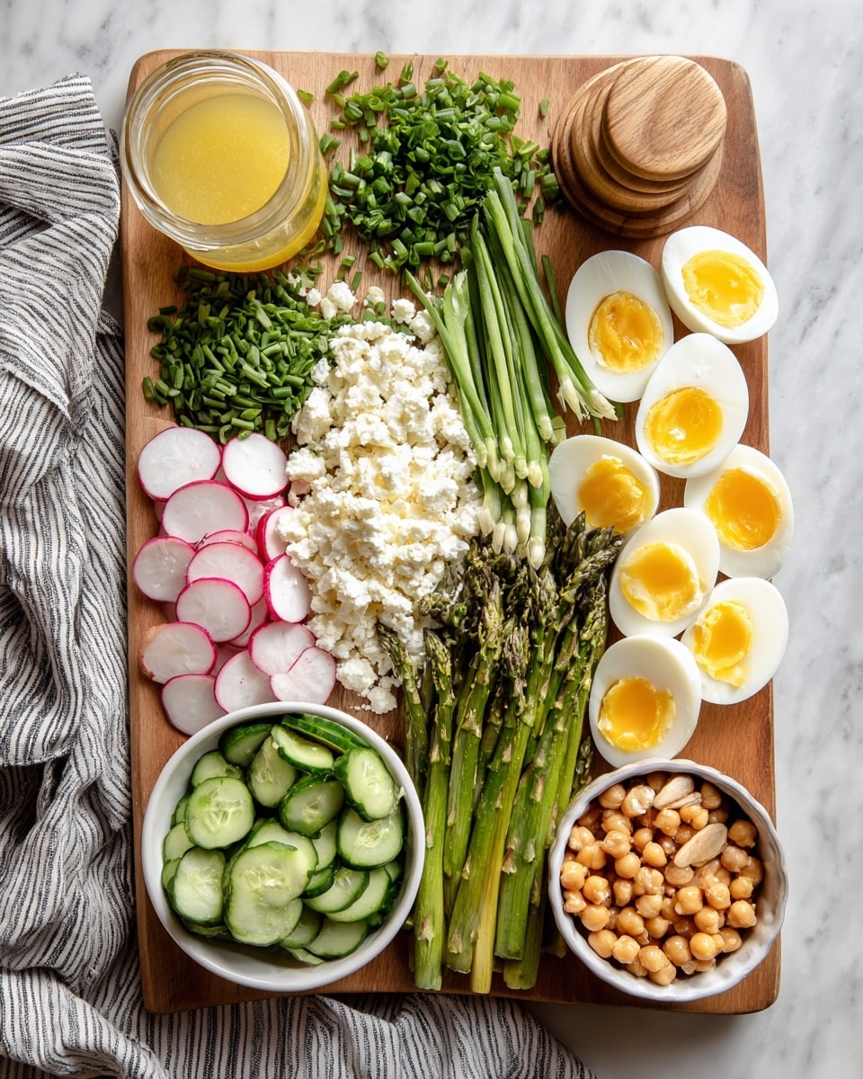A wooden board is filled with neatly arranged fresh ingredients on a white marbled surface. On the left, thinly sliced radishes with a pale pink color and white centers lie beside a small mound of chopped green chives. Next to them, a heap of white, crumbly cheese contrasts with roasted green asparagus placed to the right. Above the asparagus is a small bunch of chopped green herbs. To the far right, bright yellow sliced hard-boiled eggs with white edges are next to a pile of thinly sliced fresh cucumber rounds. Two white bowls sit on the board — one filled with bright green peas and the other with light brown pine nuts. A third white bowl holds golden chickpeas. A small jar of pale yellow dressing and a wooden salt container rest nearby, with a striped gray cloth underneath. Photo taken with an iphone --ar 4:5 --v 7