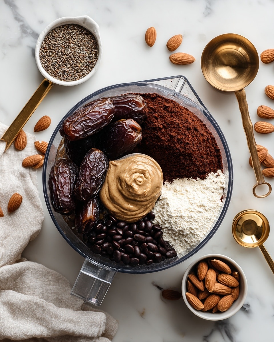 A clear food processor bowl shows a mix of several ingredients inside, arranged in layers: on the left side, large dark brown dates with a slightly wrinkled texture; on the right, a smooth light brown almond butter dollop; near the center, a small heap of dark brown cocoa powder with a soft powdery texture; next to it, a smaller pile of white powder, likely flour; and on the upper right, shiny black beans with a smooth and firm texture. Around the bowl on the white marbled surface are scattered whole almonds, a wooden spoon with flax seeds in a small white bowl, a gold measuring cup, and additional dates. A white linen cloth partially covers the left side. The photo is taken with an iphone --ar 4:5 --v 7