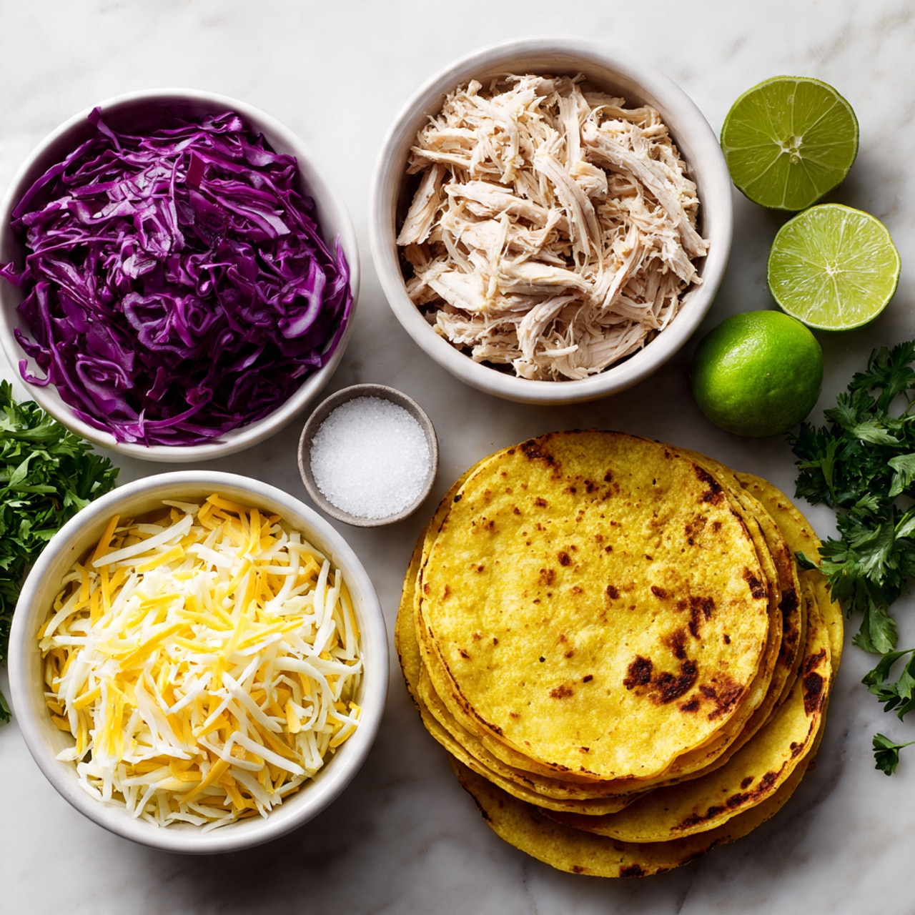 The image shows five layers arranged on a white marbled surface: at the top right, a white bowl filled with thinly sliced purple cabbage; in the center, a white bowl with shredded cooked chicken that looks moist and tender; at the bottom left, a white bowl holding a mix of shredded yellow and white cheese; at the bottom right, a neat stack of yellow corn tortillas with slightly charred edges; and a bunch of fresh green parsley with two whole limes placed near the bowls. A small white bowl of salt is also placed near the parsley. The items are neatly spread for taco preparation. photo taken with an iphone --ar 4:5 --v 7
