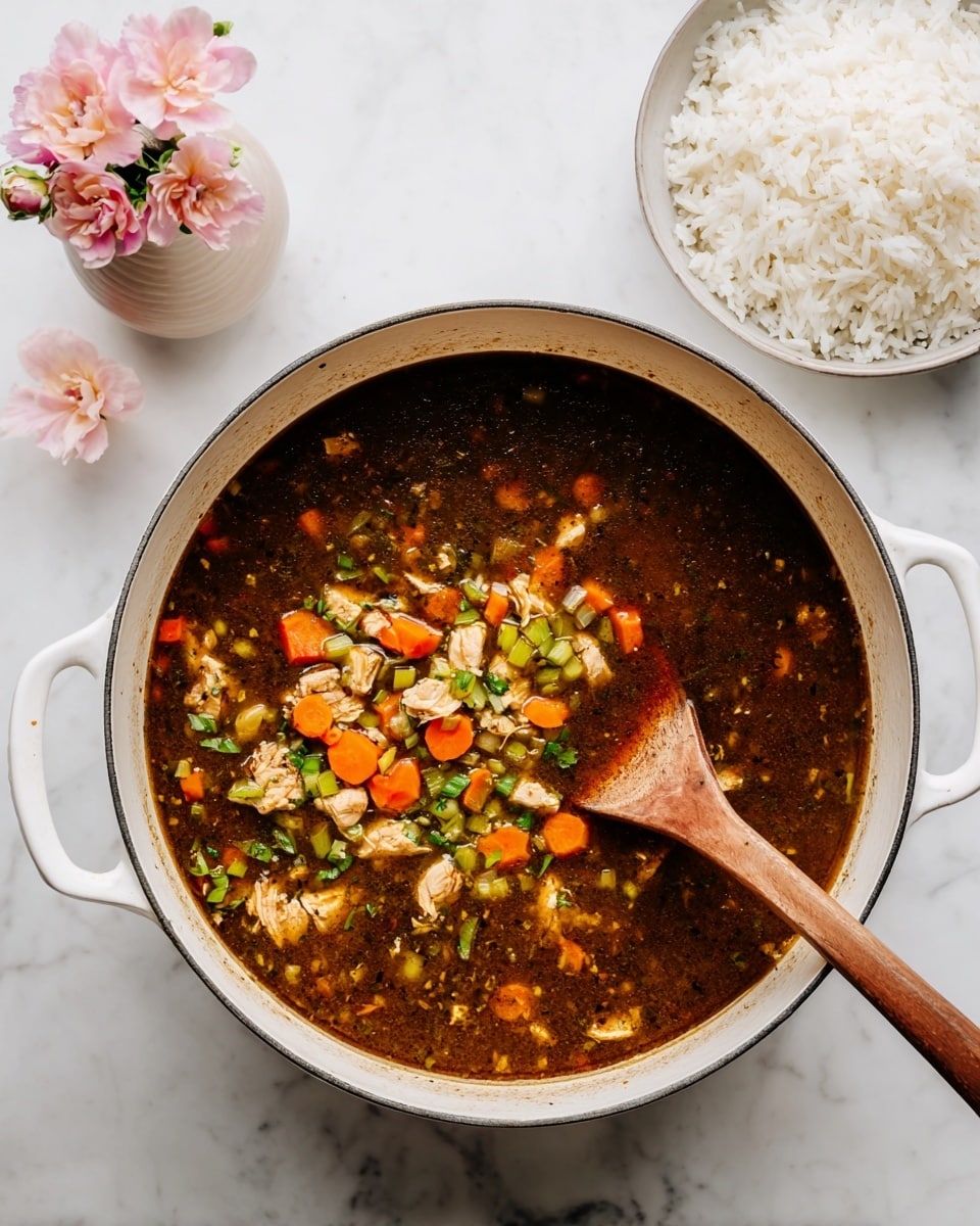 A large white pot filled with dark chicken soup that has small pieces of chicken, diced orange carrots, and chopped green celery floating in a clear brown broth, with a wooden spoon stirring the soup from the right side. In the background, there is a white plate with cooked plain white rice, and to the left, a small pale pink vase holds three light pink flowers, all placed on a white marbled surface. photo taken with an iphone --ar 4:5 --v 7