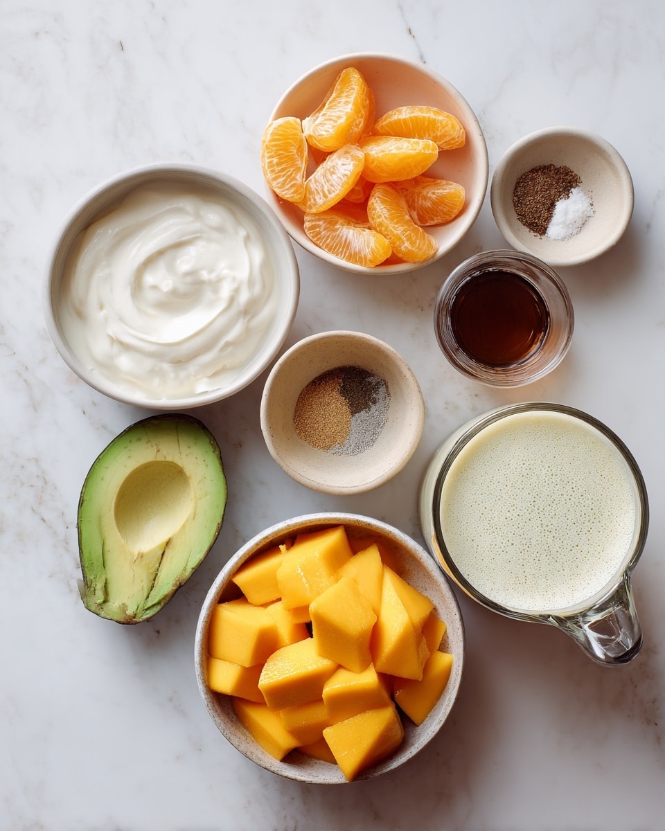 The image shows an arrangement of ingredients on a white marbled surface, including a white bowl filled with frozen bright orange mango chunks, a white bowl with peeled orange tangerine segments, a small bowl with half a light green avocado, a larger white bowl with thick white yogurt, a small beige bowl with brown spices and white salt, a tiny beige bowl with dark brown vanilla extract, and a clear glass measuring cup filled with a frothy creamy liquid. Photo taken with an iphone --ar 4:5 --v 7