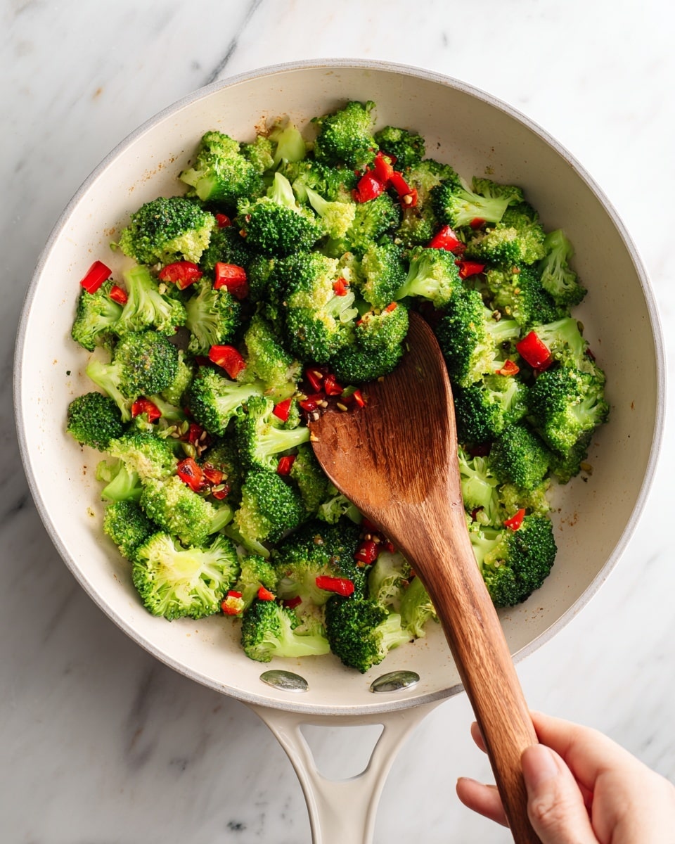 A white round pot filled with cooked shrimp, evenly scattered on top. The shrimp are pink with a slight shine, curled in shape. Mixed with the shrimp are bright green broccoli florets and small red bell pepper cubes, spread throughout the pot. The vegetables look fresh and slightly cooked, keeping their texture. A golden spoon handle rests inside the pot on the left side. The pot sits on a white marbled surface, with a glass of water to the top left and stacked white plates with black rims on the right side. photo taken with an iphone --ar 4:5 --v 7