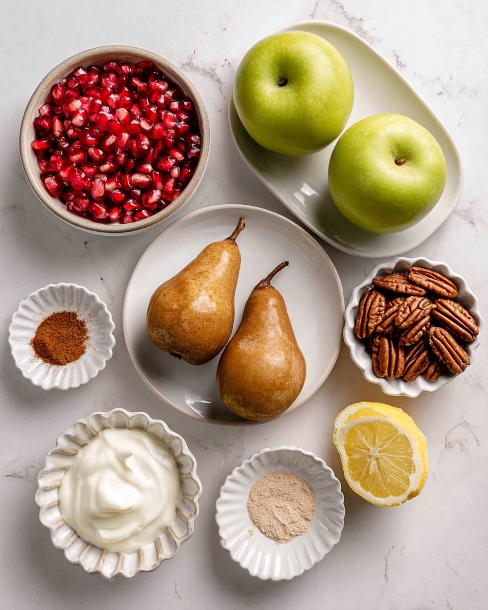 The image shows various ingredients arranged neatly on a white marbled surface. At the top left, there is a round bowl filled with bright red pomegranate seeds, shiny and translucent. To the right, a white plate holds two green apples with a smooth, shiny texture. In the center, a white plate contains two brown pears with a matte finish and slightly rough texture. Below, a small round bowl has a dollop of white coconut oil with a creamy appearance. To the right of it, there is a small scalloped white bowl full of pecans, showing their dark brown ridged shells. Near the center right, a small bowl displays a half lemon with a fresh yellow interior and a visible juicy texture. Two small dishes hold ground spices: one has a warm brown cinnamon powder and the other has a pale beige powder. The overall layout is clean and organized, with a variety of natural textures and colors visible. Photo taken with an iphone --ar 4:5 --v 7