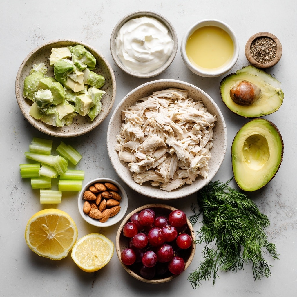 A white bowl holds four separated layers of ingredients on a white marbled surface. In the top left quarter, small pale green diced celery pieces create a fresh, textured look. Below this, in the bottom left quarter, there are dark red grapes, some whole and some sliced, showing their smooth, shiny skins. To the right, occupying the bottom right quarter, is a pile of light tan slivered almonds laying on top of each other, adding a crunchy texture. The top right quarter features a creamy, pale green mixture with small dark green dill leaves sprinkled on it, showing a soft, thick texture. A silver spoon rests inside the bowl on the right side. Photo taken with an iphone --ar 4:5 --v 7