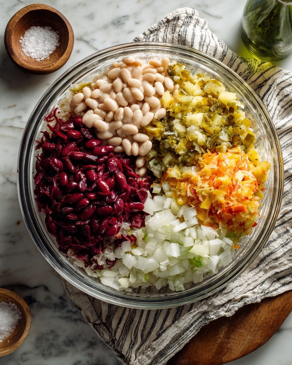 The image shows a clear glass bowl with six different layers of ingredients, each placed side by side without mixing. Starting from the top left, there is a dark red layer of kidney beans, next to that is a light beige layer of white beans. To the right of the beans is a greenish-yellow layer of chopped pickles, followed below by a yellow layer of chopped potatoes. At the bottom right, there is a white layer of diced onions, and at the bottom left, there is a light beige layer of sauerkraut over a dark red layer of chopped beets. The bowl rests on a white marbled surface with a striped cloth underneath. A small wooden bowl with coarse salt and a green bottle are partially visible nearby. photo taken with an iphone --ar 4:5 --v 7