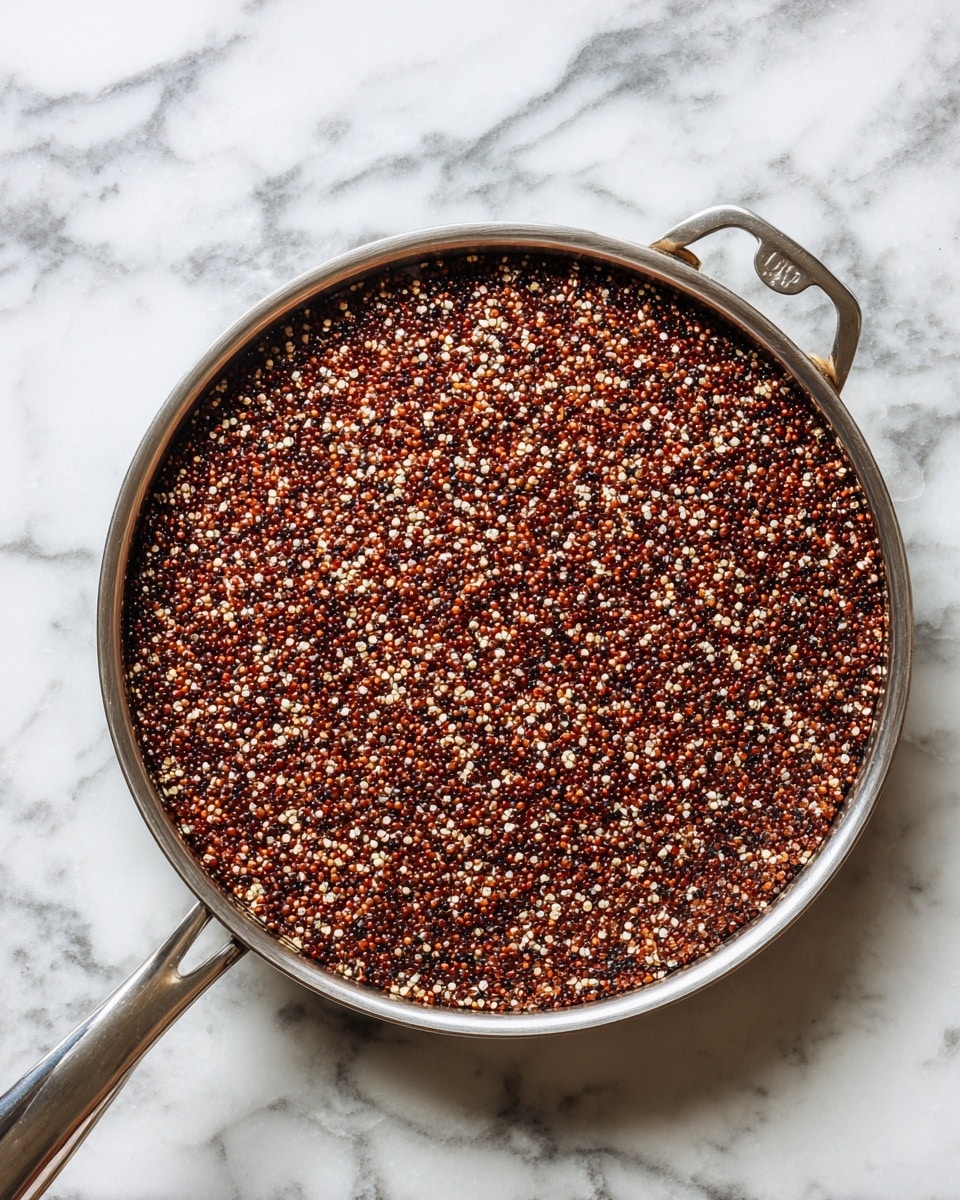 A top view of a single layer of cooked red, black, and white quinoa filling a round silver pan with a metal handle on a white marbled surface photo taken with an iphone --ar 4:5 --v 7