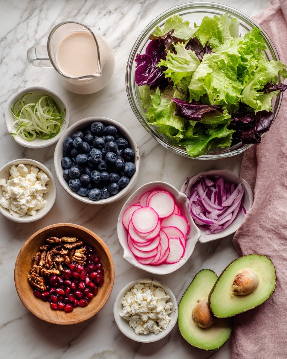A collection of fresh salad ingredients is arranged on a white marbled surface: a large clear glass bowl filled with different green and purple leafy lettuce types, a white bowl full of blueberries, a white bowl with bright pink and green radish slices, a small white bowl of crumbly white cheese, a white bowl with thinly sliced purple onions, and a smaller white bowl with shiny red pomegranate seeds. There's also a wooden bowl holding glossy toasted nuts or seeds, and two halves of a ripe avocado with bright green flesh and dark brown seeds lying on a light pink cloth nearby. A small clear glass pitcher contains a creamy, light pink dressing. Photo taken with an iphone --ar 4:5 --v 7