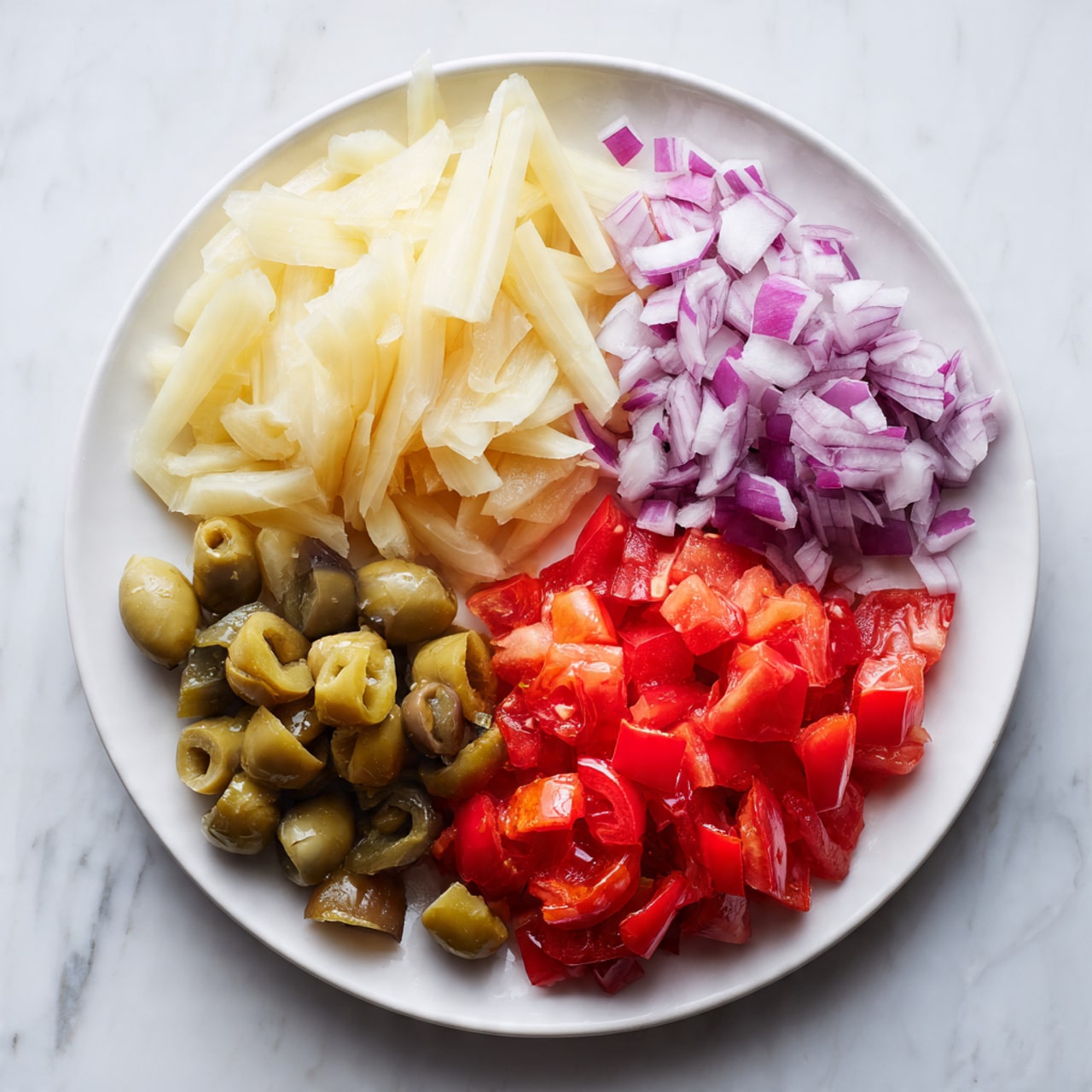 A white plate sits on a white marbled surface filled with five sections of chopped vegetables. Starting from the top left is a layer of pale, creamy yellow bamboo shoots with a slightly soft texture. To the right is a cluster of finely chopped light purple onions with a moist and crisp look. In the bottom right is a bright red pile of chopped tomatoes with a juicy and slightly shiny texture. To the bottom left is a mix of darker red bell peppers with a firm texture, and next to them towards the left center is a section of green olives cut into chunks with a glossy, smooth surface showing their fleshy inside. The layers are evenly spread and look fresh and colorful. photo taken with an iphone --ar 4:5 --v 7
