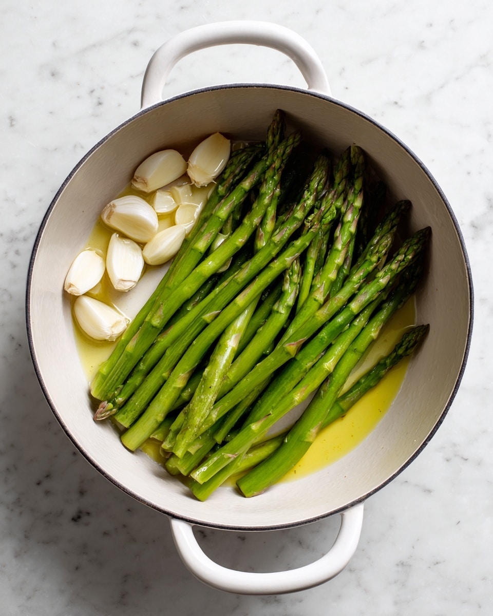 A white pot with two handles is shown from above, placed on a white marbled surface. Inside the pot, there are thin, long green asparagus strips lying mostly in the center and right side, with a few asparagus tips visible. On the left side of the pot, there are several thin white slices of garlic scattered nearby a small pool of light yellow oil that covers the bottom of the pot. The textures include the smooth, oily base, crisp asparagus strips, and firm garlic slices. Photo taken with an iphone --ar 4:5 --v 7