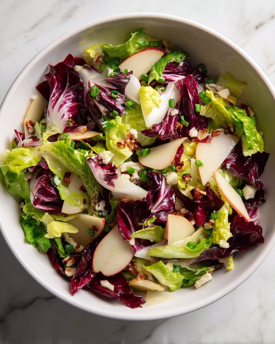A white plate with floral green leaves pattern holds a fresh mixed salad arranged in one layer, featuring bright green romaine and red radicchio leaves, sliced pale yellow apple wedges scattered throughout, crumbled white cheese pieces, and small brown walnut chunks sprinkled evenly on top. The salad has a light dressing with visible black pepper specks. To the left, a white bowl contains light mustard-yellow dressing with a small spoon inside. In the upper right corner, chunks of blue-veined white cheese are placed on a wooden board. The surface under the plate is a white marbled texture, and a woman's hand with a fork is partially visible on the left edge near the salad. A white and gray striped cloth napkin is partially under the plate on the right side. photo taken with an iphone --ar 4:5 --v 7