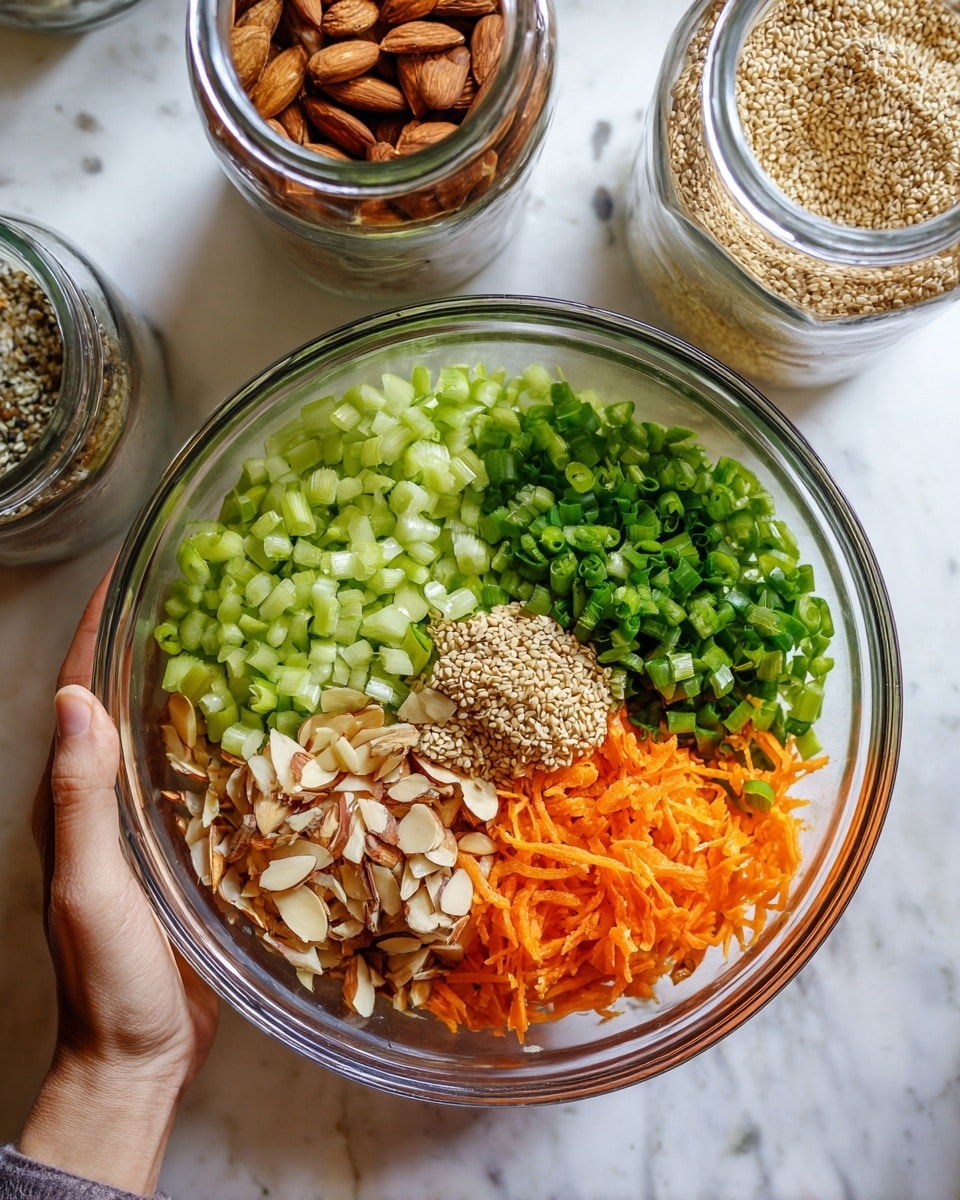 A clear glass bowl held by a woman's hand contains a colorful salad with five distinct layers: light green celery slices on the top left, bright green chopped spring onions on the top right, orange shredded carrots on the right center, light brown toasted almond slices on the bottom left, and a small heap of tan sesame seeds in the center. The bowl is placed on a white marbled textured surface with two glass jars above it – one filled with sliced almonds and the other with sesame seeds, the jar lids open. Photo taken with an iphone --ar 4:5 --v 7