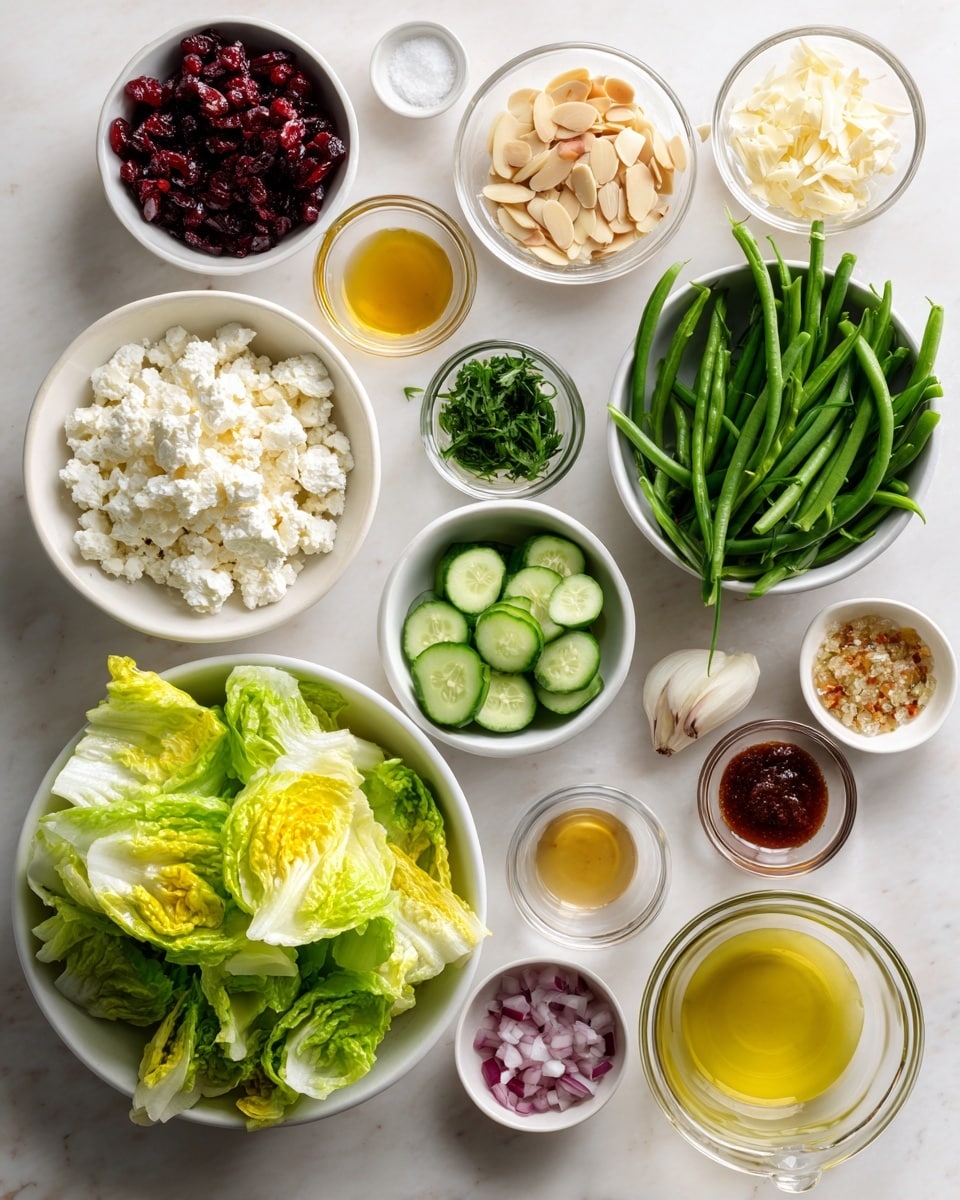 The image shows a variety of fresh salad ingredients arranged separately on a white marbled surface. On the bottom left, a white bowl is filled with bright green lettuce leaves with yellow tips. To the right of it, there is a small glass bowl filled with sliced almonds. Above that, a white bowl holds green cucumber slices. Next to it is a small bowl of chopped green herbs. Above the herbs, a large bowl contains fresh green beans. To the left of the green beans, a bowl holds white cottage cheese. To the left of that, a small glass bowl is filled with dark red dried cranberries. On the top right, there are four small white bowls with various sauces and seasonings, including a light mustard yellow, an amber-colored sauce, minced garlic, and salt with pepper. Next to these, a small glass cup contains a yellow liquid, likely oil, and a glass with a red liquid, possibly vinegar. A glass cup below the small bowls holds finely chopped red onions. The items are neatly spaced and all the bowls are white except the glass ones, placed on a soft white marbled background, photo taken with an iphone --ar 4:5 --v 7