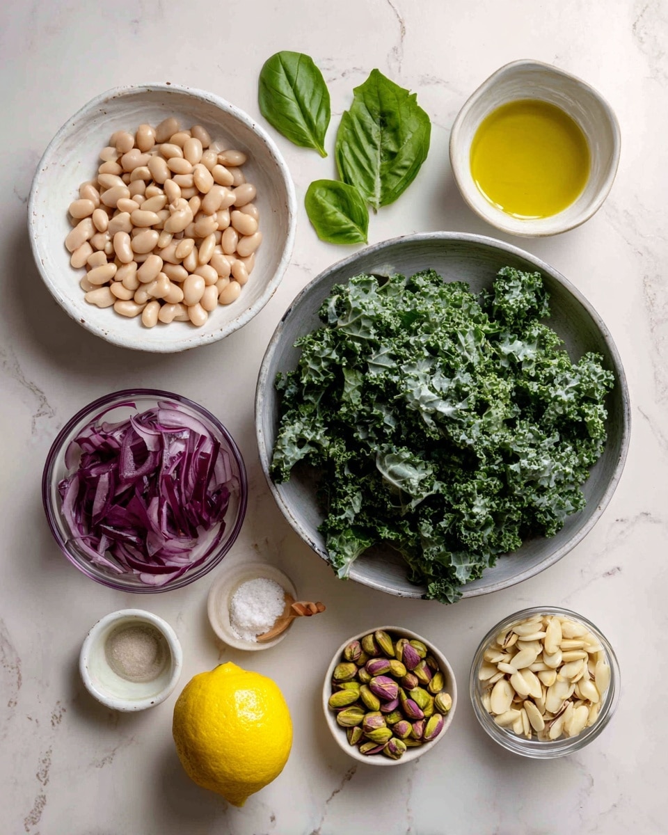 The image shows ingredients on a white marbled surface. On the right, there is a large silver bowl filled with chopped green kale leaves, with curly texture. To its left, there is a white small bowl with light brown beans, and behind it, three large green basil leaves rest flat on the surface. Below the beans, there is a small clear glass bowl of thinly sliced purple-red onions. To the right of the onion bowl are two small clear glass bowls; the top one contains mixed green and brown pistachios, and the bottom one holds pale off-white pine nuts. Next to them are two small white dishes, one with golden olive oil and the other with light beige creamy dressing. Below these is a bright yellow lemon placed directly on the surface. There is also a small white bowl with coarse salt and a tiny wooden spoon inside it. The arrangement is clean and organized, with soft natural lighting. Photo taken with an iphone --ar 4:5 --v 7