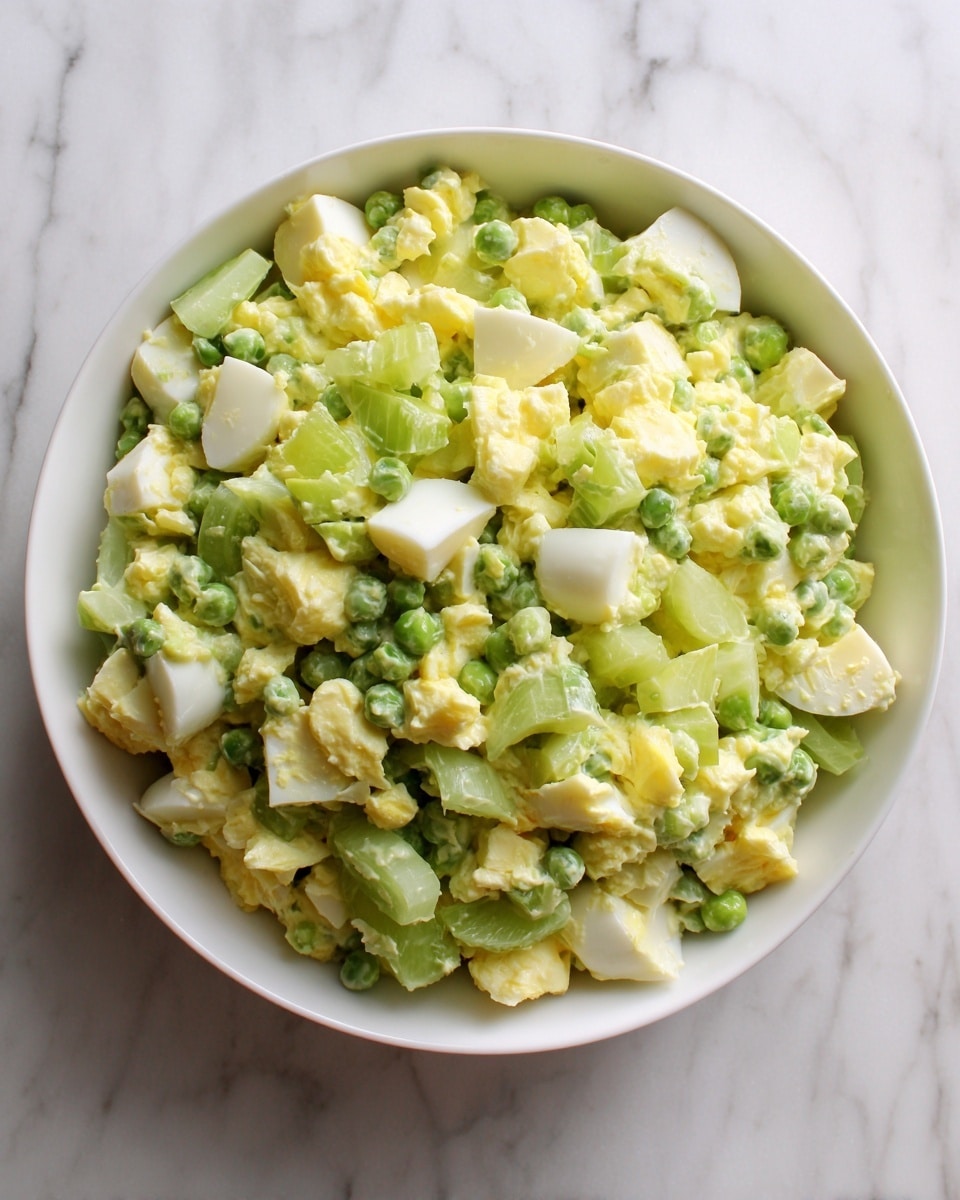 A white bowl sits on a white marbled surface, filled with a mixed salad of chopped boiled egg, green peas, and sliced celery. The chopped egg pieces are pale yellow and white, scattered evenly throughout the bowl. The green peas provide a vibrant green color, while the celery slices are light green with a slightly translucent texture. The colors are fresh and bright, with a soft and slightly chunky texture visible in each ingredient. The mix looks lightly tossed, with none of the ingredients piled too high or dominant. photo taken with an iphone --ar 4:5 --v 7