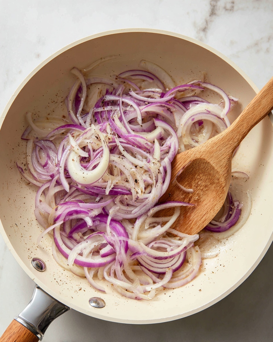 The image shows a light brown frying pan with a white inside surface, sitting on a stove. Inside the pan, there are thin slices of purple and white onions being lightly cooked and stirred with a smooth wooden spatula. The onions have a mix of translucent white parts and some brown edges indicating they are being gently fried. The background consists of a white marbled surface. photo taken with an iphone --ar 4:5 --v 7