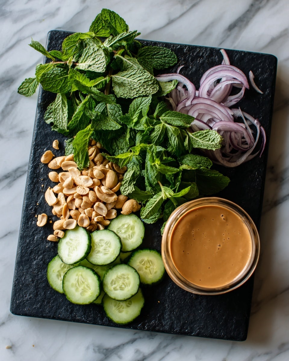 The image shows a black cutting board on a white marbled surface with several fresh ingredients arranged neatly. There is a pile of chopped peanuts in pale beige color near the center, next to thin slices of light green cucumbers placed in a small mound on the right. Above the peanuts, bright green fresh herbs including mint and cilantro leaves are layered, with some light purple thinly sliced onions on the top right side. A glass jar filled with smooth light brown peanut sauce sits on the board's right edge. The person's woman's hand is not visible but the image is taken from the viewpoint of someone standing over the board. Photo taken with an iphone --ar 4:5 --v 7
