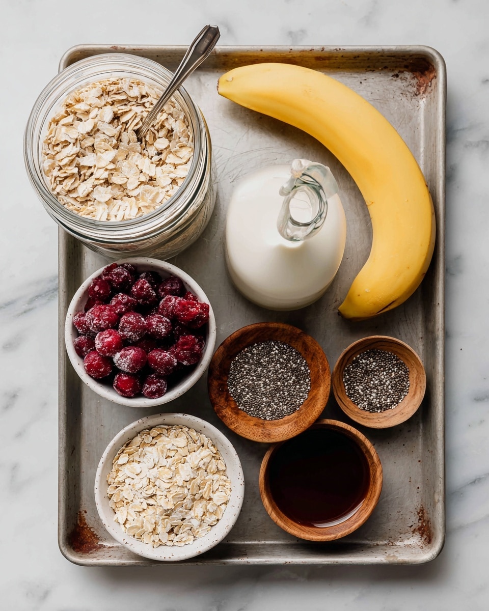 A metal baking tray sits on a white marbled surface, holding various ingredients: a large glass jar filled with pale beige oats with a silver spoon inside, a small clear glass bottle of white milk, a small clear glass bowl of dark amber honey, a white bowl filled with round, deep red frozen cherries, a whole yellow banana placed diagonally, a wooden bowl full of small black and white chia seeds, and two small wooden bowls with dark brown and very dark liquid respectively. The textures range from smooth and creamy milk to rough oats and frozen cherries, with warm wooden tones of the bowls contrasting the cold ingredients. Photo taken with an iphone --ar 4:5 --v 7
