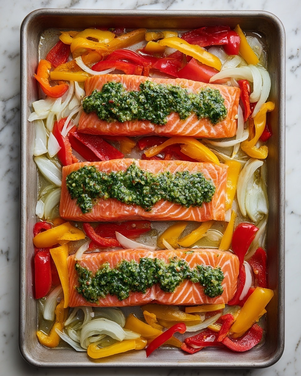 The image shows a metal baking tray filled with three pieces of raw salmon, each topped with a green herb sauce. The salmon is light orange with white lines of fat, positioned in the center, lined up side by side. Surrounding the salmon are chopped bell peppers in red, yellow, and green colors along with slices of white onion, all scattered evenly around and under the salmon pieces. The tray is inside an oven with a white marbled surface in the background. Photo taken with an iphone --ar 4:5 --v 7
