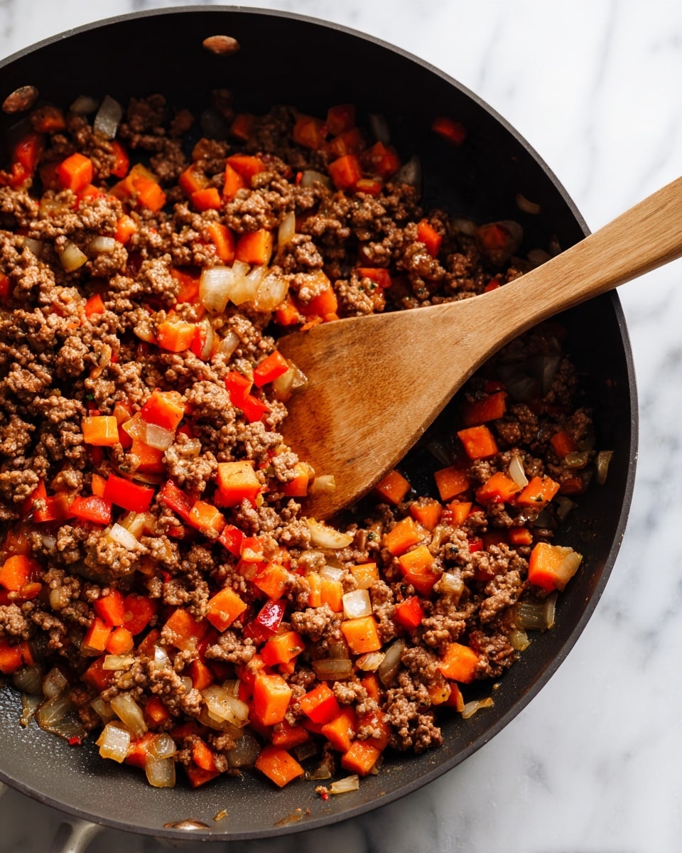 A close-up view of a black pan filled with a cooked mix of ground meat and diced vegetables in one layer. The mixture includes dark brown ground meat, orange carrots, white onions, and red bell peppers, all cooked and slightly caramelized. A brown wooden spoon rests inside the pan, partially stirring the ingredients. The pan sits on a white marbled surface. photo taken with an iphone --ar 4:5 --v 7